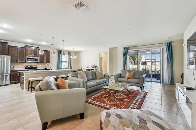 living room with an inviting chandelier, sink, and light tile patterned flooring