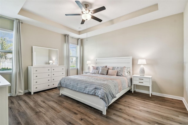 bedroom featuring baseboards, a raised ceiling, and wood finished floors