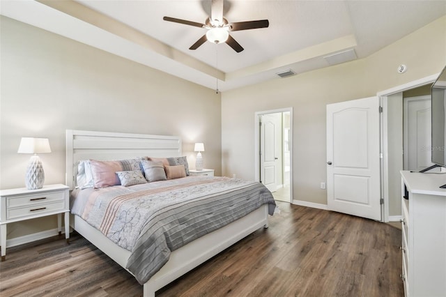 bedroom featuring dark wood-type flooring, a raised ceiling, and ceiling fan