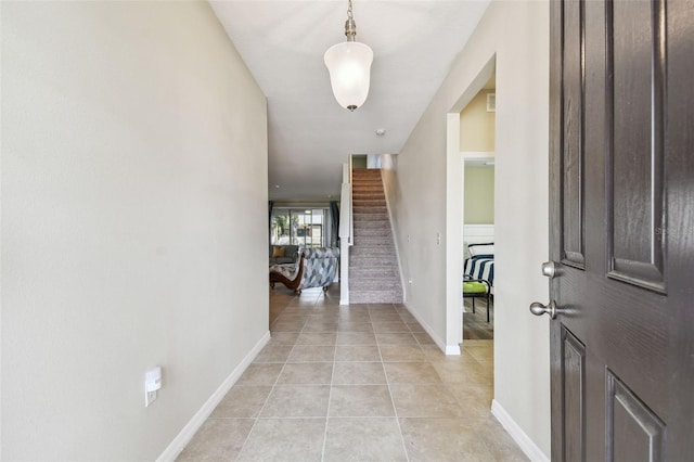 hall featuring light tile patterned flooring, stairs, and baseboards