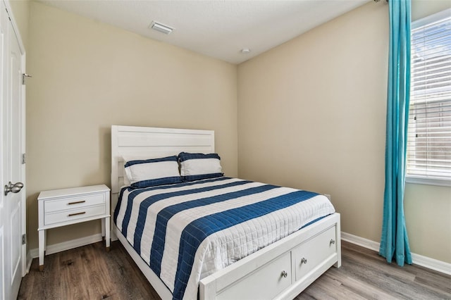 bedroom featuring visible vents, baseboards, and wood finished floors