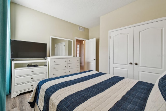 bedroom with visible vents, a textured ceiling, a closet, and wood finished floors