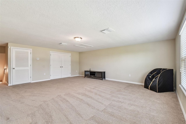 unfurnished room featuring light carpet and a textured ceiling