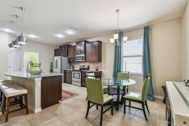 kitchen with tasteful backsplash, a breakfast bar area, hanging light fixtures, stainless steel appliances, and a center island with sink