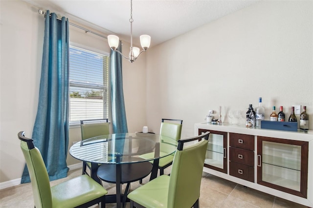 dining area featuring light tile patterned floors, a chandelier, a dry bar, and baseboards