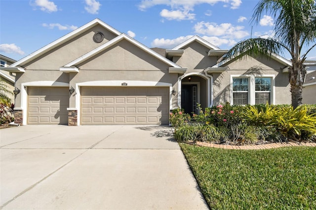 view of front of property featuring stone siding, stucco siding, driveway, and a garage