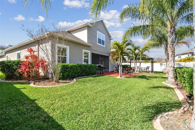 rear view of house featuring a patio area, stucco siding, a yard, and fence