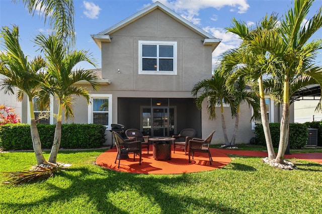 rear view of property with stucco siding, a lawn, and a patio area