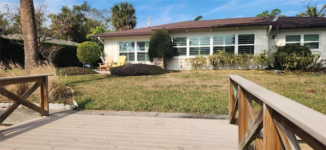 rear view of property with a wooden deck and a lawn