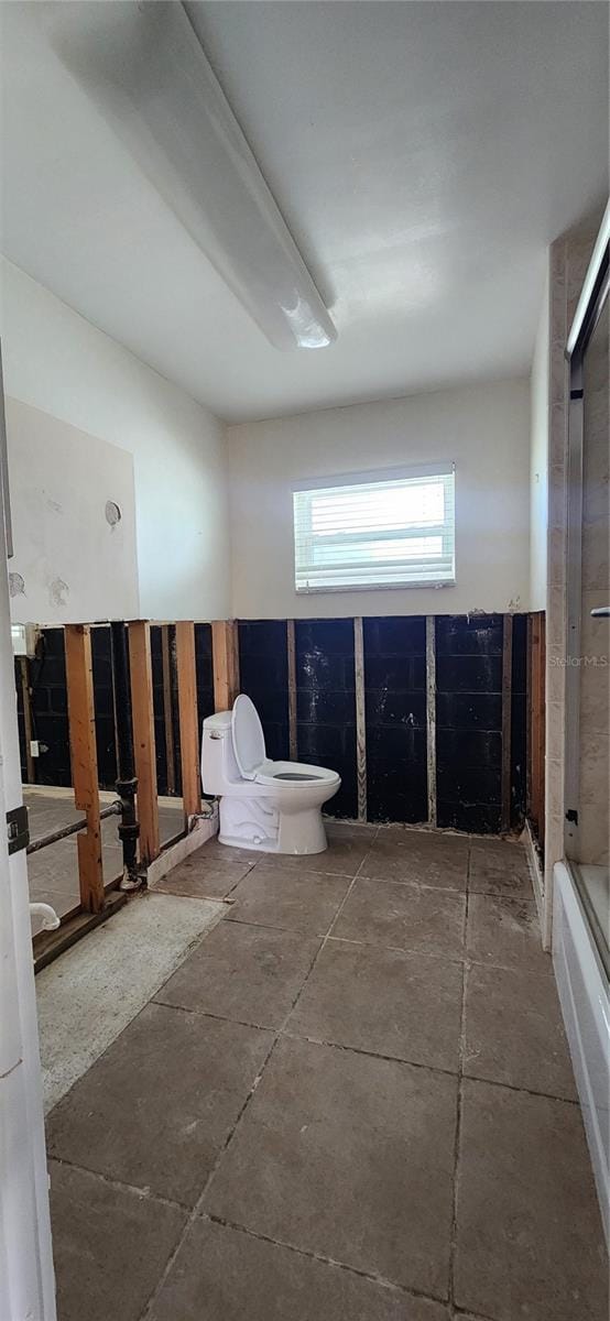 bathroom featuring a shower with door and toilet