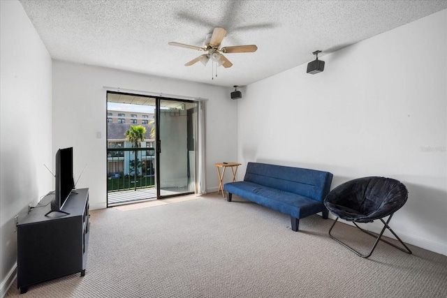 living area featuring ceiling fan, carpet floors, and a textured ceiling