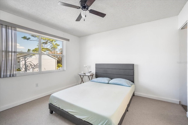 carpeted bedroom with ceiling fan and a textured ceiling