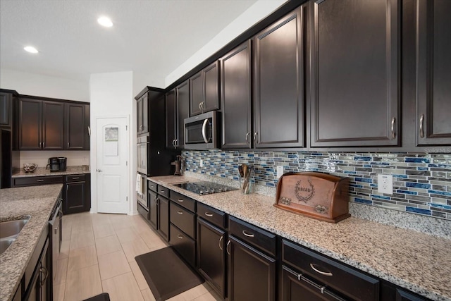 kitchen with light stone counters, dark brown cabinetry, stainless steel appliances, and tasteful backsplash