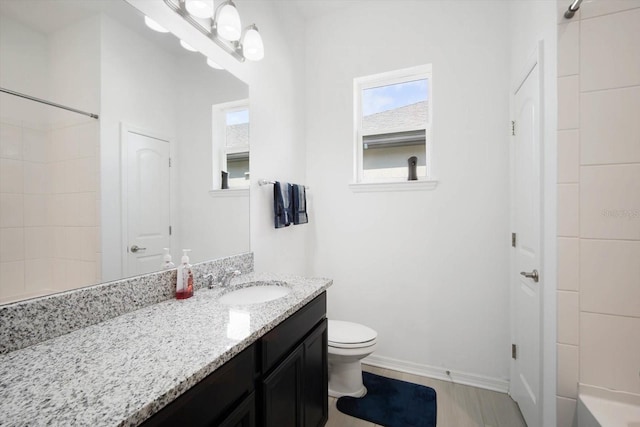 bathroom with vanity, tiled shower, and toilet