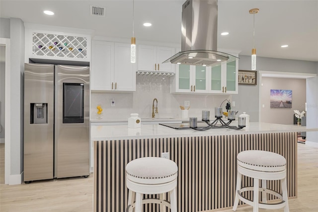 kitchen featuring pendant lighting, a kitchen breakfast bar, stainless steel refrigerator with ice dispenser, white cabinets, and island exhaust hood