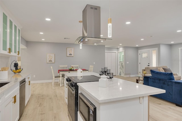 kitchen featuring pendant lighting, white cabinetry, stainless steel appliances, a center island, and island exhaust hood