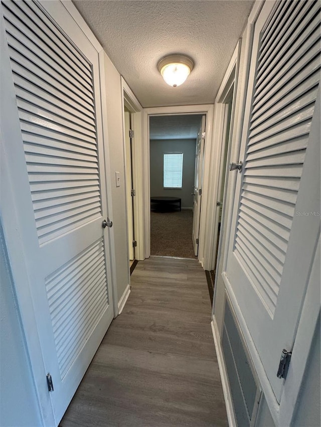 corridor with dark hardwood / wood-style flooring and a textured ceiling