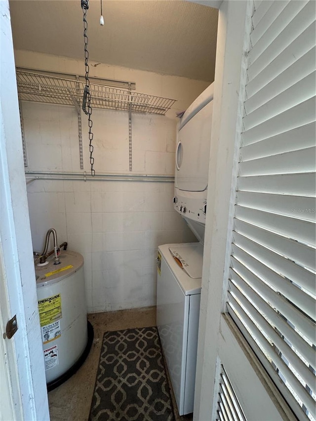 washroom featuring stacked washer and clothes dryer and water heater