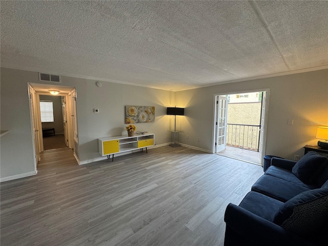 unfurnished living room with hardwood / wood-style floors, a wealth of natural light, ornamental molding, and a textured ceiling