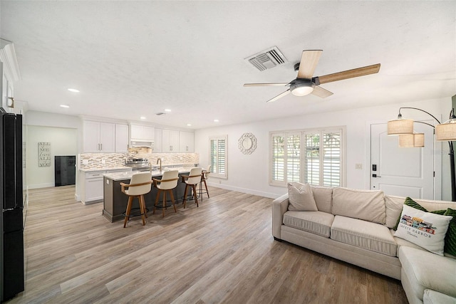 living room featuring sink, a textured ceiling, light hardwood / wood-style flooring, and ceiling fan