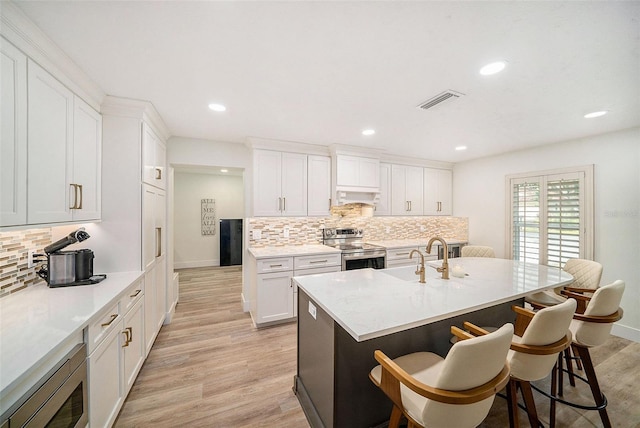 kitchen featuring sink, a breakfast bar area, white cabinets, stainless steel appliances, and custom range hood