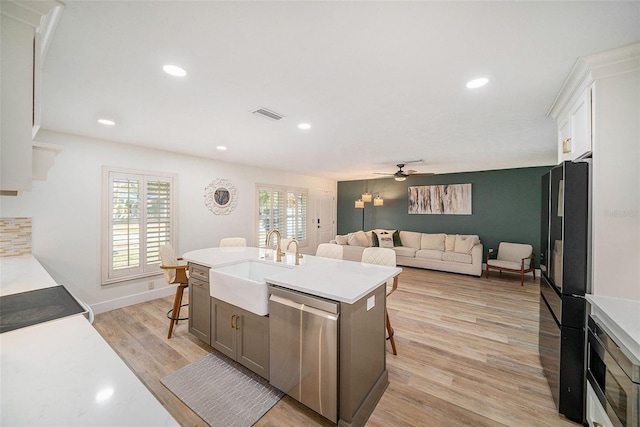 kitchen featuring a kitchen bar, sink, white cabinetry, a center island with sink, and stainless steel appliances