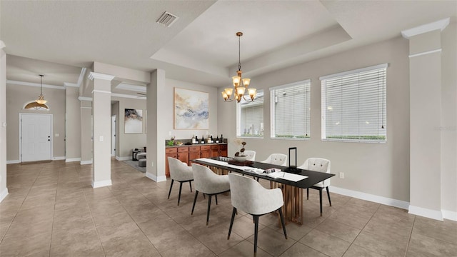 dining area featuring a raised ceiling, light tile patterned flooring, an inviting chandelier, and ornate columns