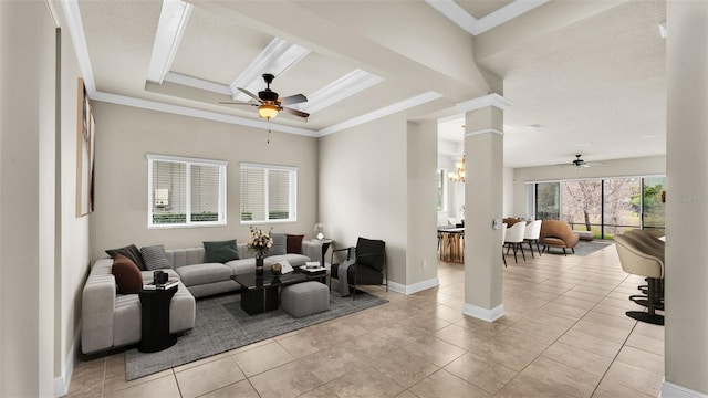 tiled living room with crown molding, a tray ceiling, ceiling fan with notable chandelier, and decorative columns