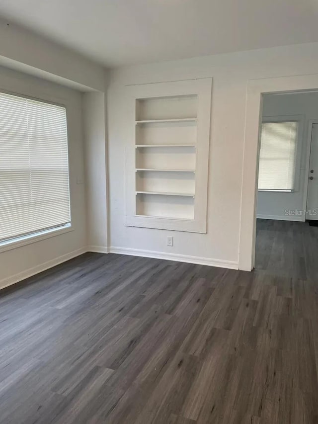 empty room with dark wood-type flooring and built in shelves