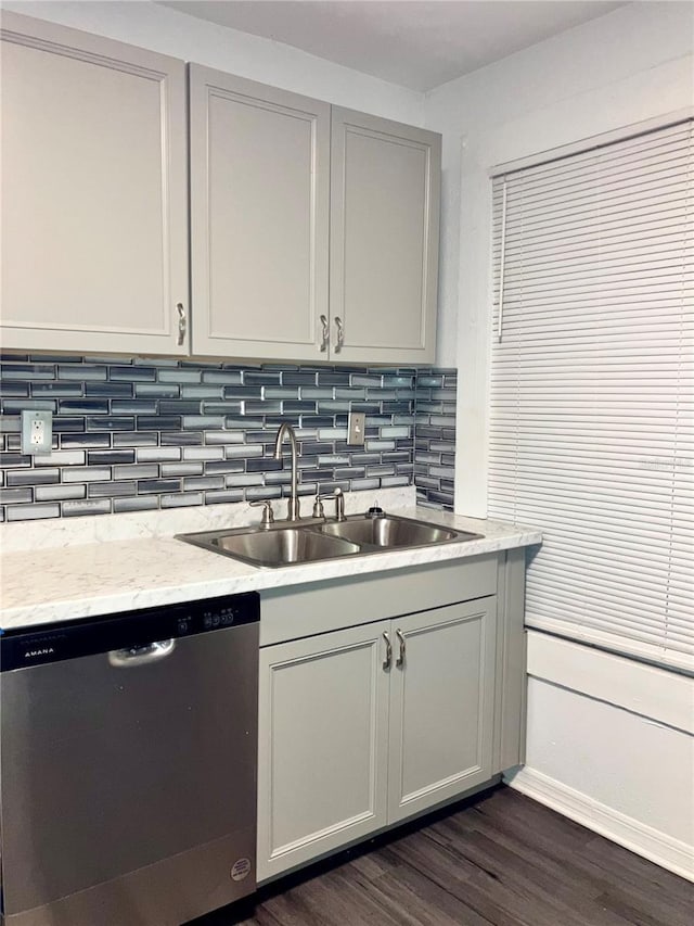 kitchen with dishwasher, sink, decorative backsplash, light stone counters, and dark wood-type flooring