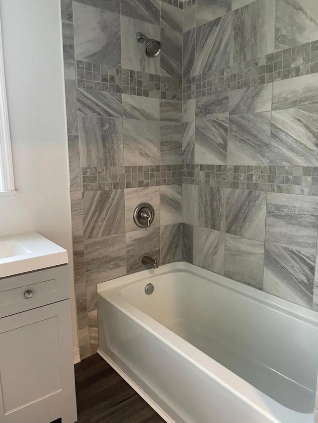 bathroom with tiled shower / bath combo, vanity, and hardwood / wood-style floors