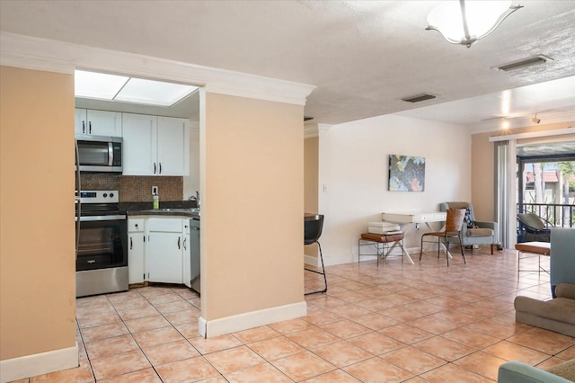 kitchen with white cabinetry, stainless steel appliances, light tile patterned floors, and backsplash