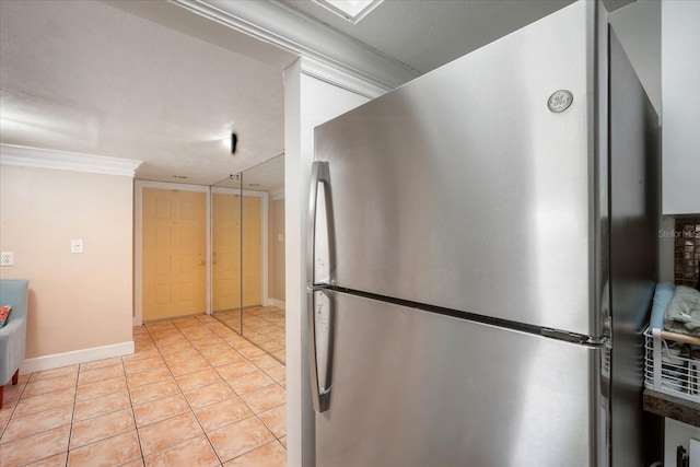 kitchen with ornamental molding, stainless steel refrigerator, and light tile patterned flooring