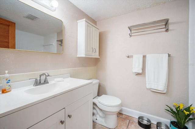 bathroom featuring tile patterned floors, toilet, a textured ceiling, and vanity