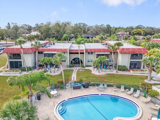 rear view of house with a community pool, a yard, and a patio area