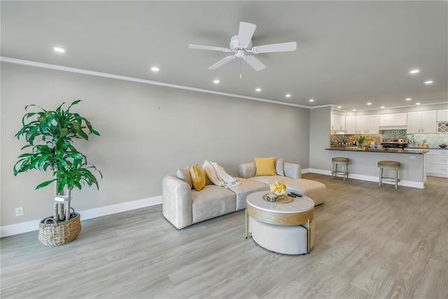 living room featuring crown molding, ceiling fan, and light wood-type flooring