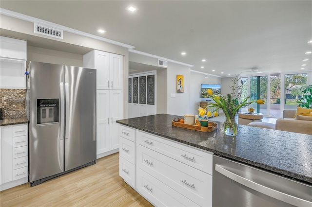 kitchen with white cabinetry, appliances with stainless steel finishes, light hardwood / wood-style flooring, and dark stone counters