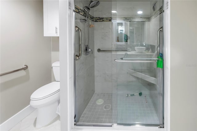 bathroom featuring a shower with door and toilet