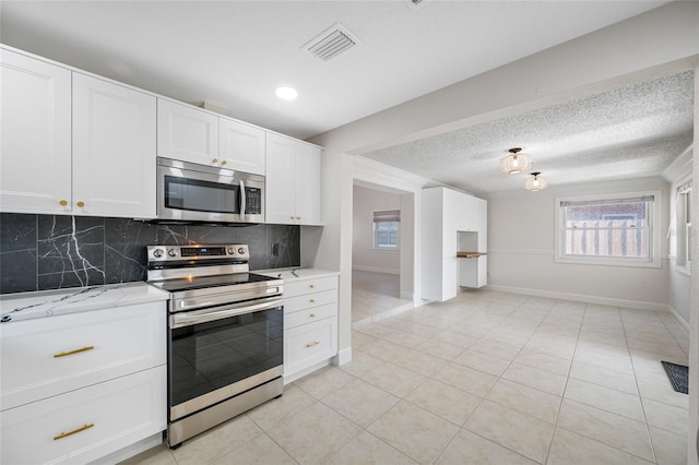 kitchen with appliances with stainless steel finishes, light stone countertops, decorative backsplash, and white cabinets