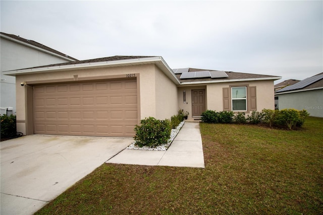 ranch-style home with an attached garage, driveway, stucco siding, roof mounted solar panels, and a front yard