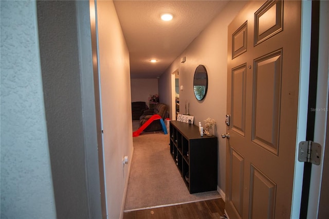 hallway with a textured ceiling, dark wood-style flooring, and baseboards