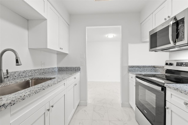 kitchen featuring light stone countertops, white cabinetry, appliances with stainless steel finishes, and sink