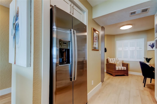 kitchen with stainless steel fridge with ice dispenser, light hardwood / wood-style floors, and white cabinets