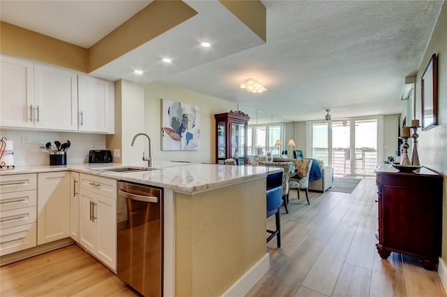 kitchen with sink, stainless steel dishwasher, kitchen peninsula, and white cabinets