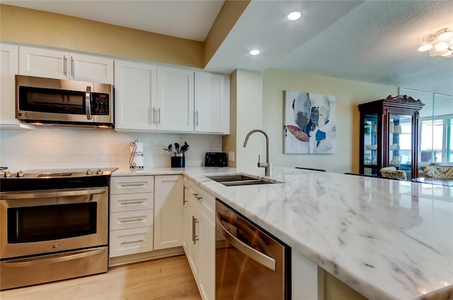 kitchen featuring light stone counters, appliances with stainless steel finishes, sink, and white cabinets