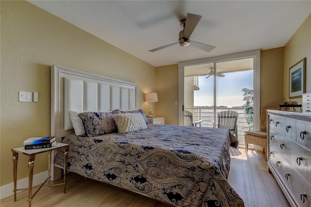 bedroom with access to exterior, a wall of windows, light hardwood / wood-style floors, and ceiling fan