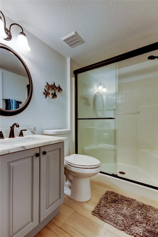 bathroom with vanity, wood-type flooring, a textured ceiling, toilet, and walk in shower