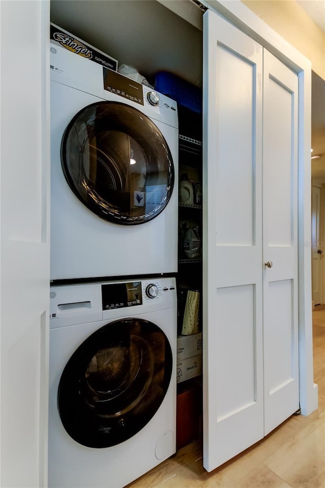 laundry area with stacked washer and dryer and light hardwood / wood-style floors