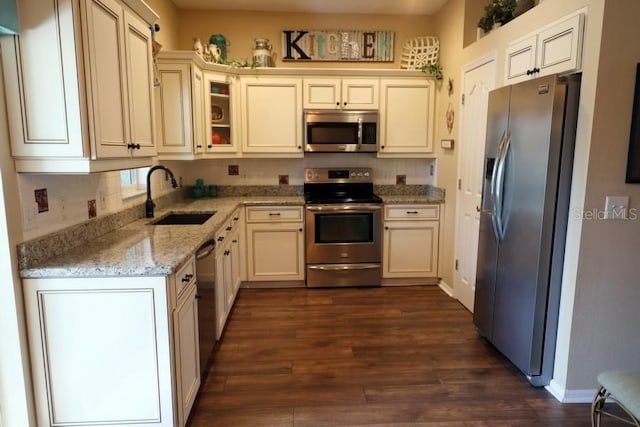 kitchen featuring sink, dark hardwood / wood-style flooring, light stone counters, stainless steel appliances, and cream cabinetry