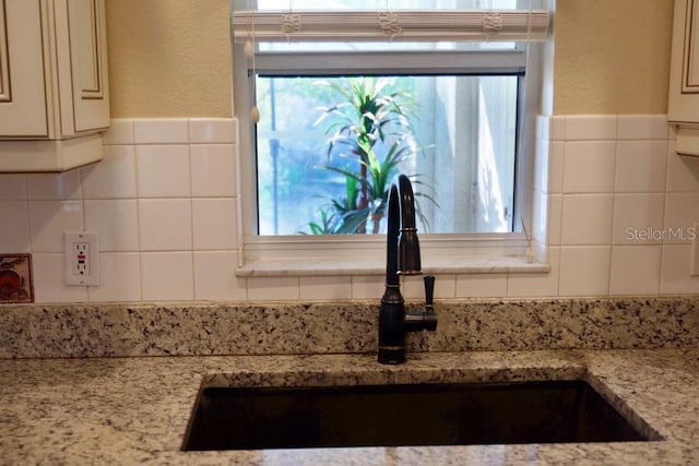 room details featuring light stone countertops and sink